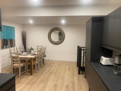 a dining room with a table and chairs and a mirror at Sleeps7-Parking-Garden-Patio in Johnstone