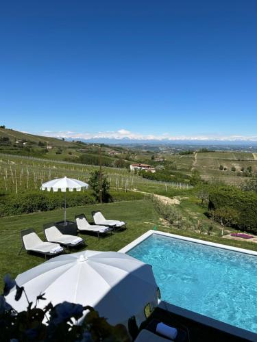 a swimming pool with an umbrella and some chairs at Borgo Piani - Camere di Charme in Mango