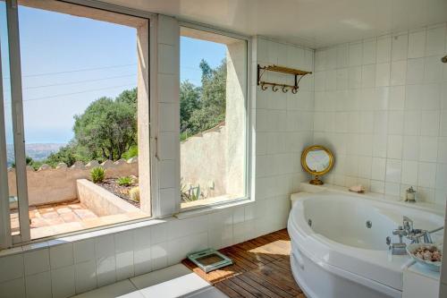 LOU MAS SOUBRAN VI2083 by RIVIERA HOLIDAY HOMES في نيس: حمام مع حوض استحمام و نافذة كبيرة