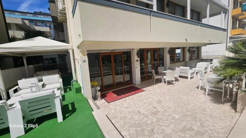 une terrasse avec des chaises blanches et un parasol dans l'établissement Hotel Annalisa, à Riccione