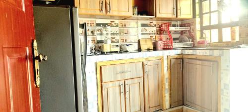 a kitchen with wooden cabinets and a refrigerator at Maridadi place in Kakamega