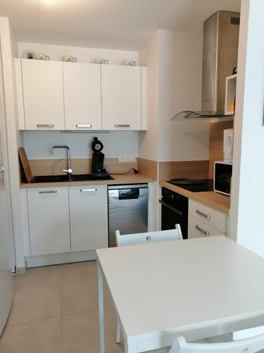 une cuisine avec des armoires blanches et une table blanche dans l'établissement Domaine de la lumière, à Saint-Jean-de-Monts