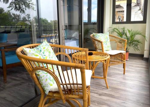 un patio con sillas de mimbre, una mesa y una ventana en Residence Le Point Choisy en Pointe aux Cannoniers