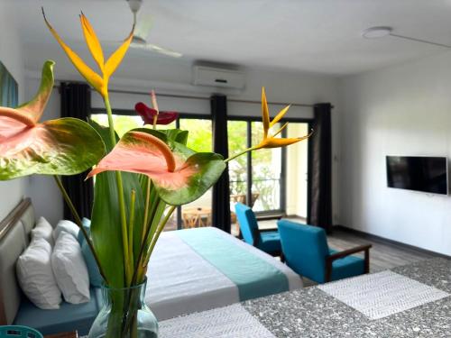 a vase with flowers on a table in a bedroom at Residence Le Point Choisy in Pointe aux Cannoniers