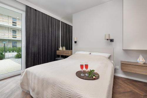 a bedroom with a bed with two glasses of wine at 5 minut do Plaży - Apartament MORZETU z Tarasem by Renters in Gąski
