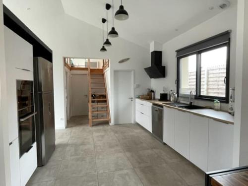 une cuisine avec des placards blancs et une grande fenêtre dans l'établissement Maison Contemporaine Andernos, à Andernos-les-Bains