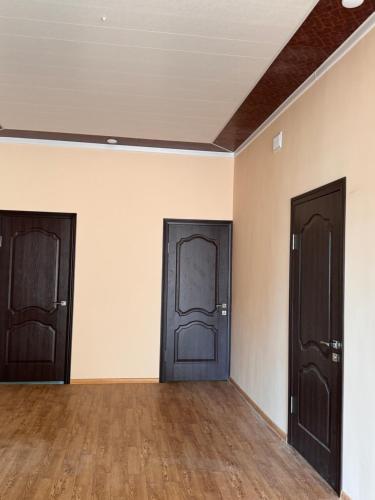 two doors in an empty room with wooden floors at Достук in Osh