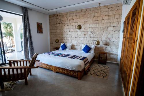 a bedroom with a bed and a brick wall at Villa Kamilia Essaouira in Essaouira