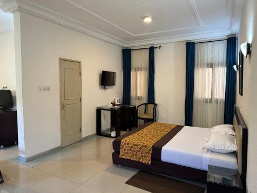 Habitación de hotel con cama y TV en Hotel le Pelican, en Lomé