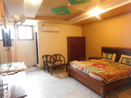 um quarto com uma cama e uma cadeira num quarto em Hotel Da Ville em Abbottabad