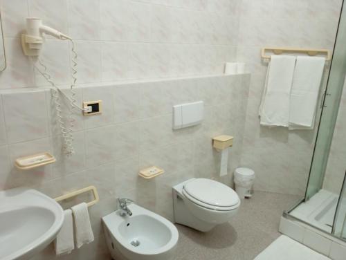 a white bathroom with a toilet and a sink at Hotel Meridiana in Arbus