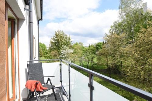 a chair on a balcony with a view of trees at Apartamenty Pod Gwiazdami in Ustroń