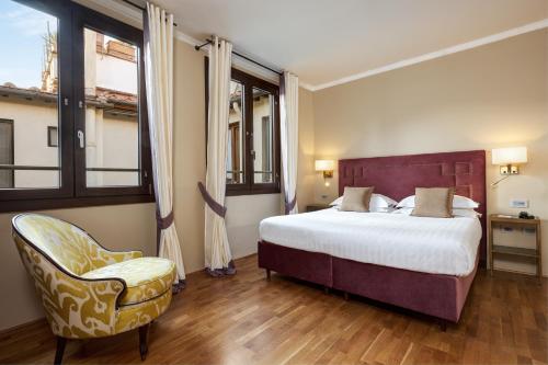 a bedroom with a large bed and a chair at Grand Hotel Cavour in Florence