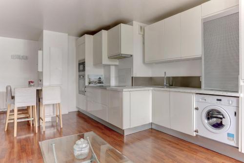 une cuisine avec des armoires blanches et une machine à laver dans l'établissement L'Abri Douillet - Mantes la jolie, à Mantes-la-Jolie