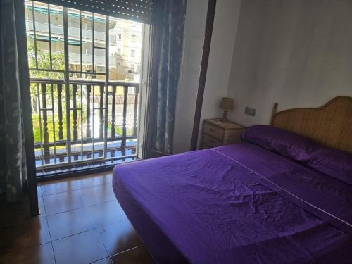 1 Schlafzimmer mit einem lila Bett und einem Balkon in der Unterkunft CASA CUNIT in Cunit
