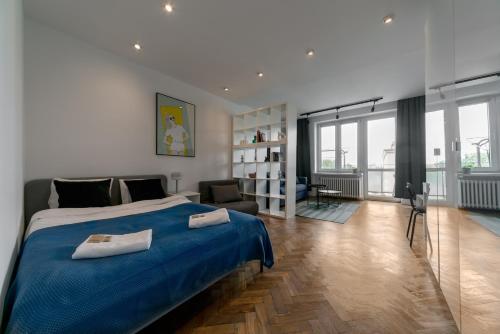 a bedroom with a blue bed and a living room at Warsaw Concierge Grójecka View in Warsaw