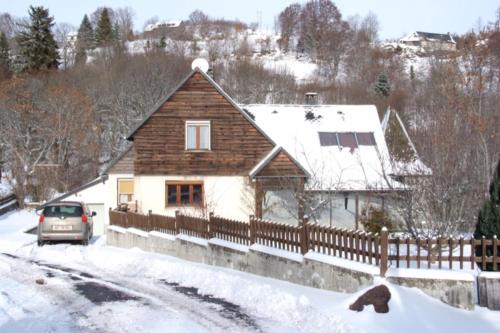 une maison avec une clôture dans la neige dans l'établissement Villa Nina, à Besse-et-Saint-Anastaise