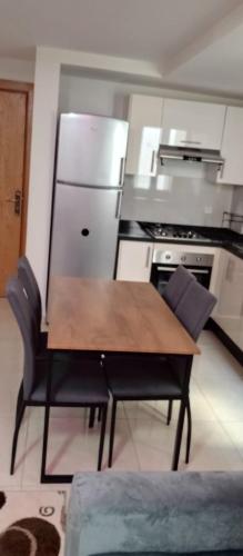 a kitchen with a wooden table and a refrigerator at Adan Beach appartment in front of Atlantic in Aourir