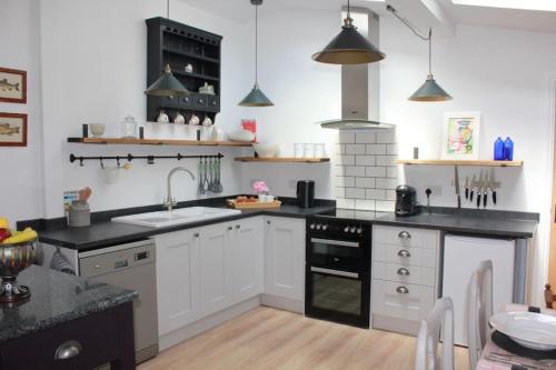a kitchen with white cabinets and black counter tops at The Pitstop in Sidlesham