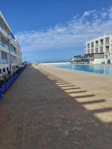 a walkway next to a beach next to a building at Adan Beach appartment in front of Atlantic in Aourir