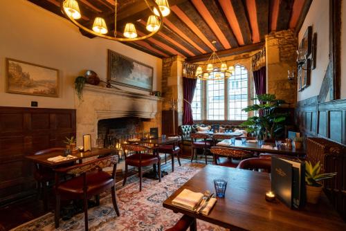 a restaurant with tables and chairs and a fireplace at The George Inn & Plaine in Norton Saint Philip