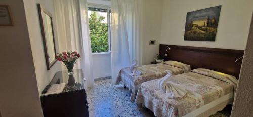 a bedroom with two beds and a window at Hotel Dora in Levanto