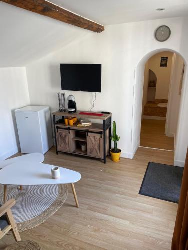 un salon avec une télévision et une table dans l'établissement Gîte de Courdoux, à Sargé Les Le Mans 