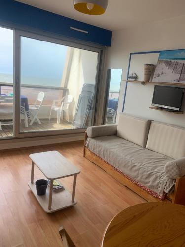 ein Wohnzimmer mit Sofa und Tisch in der Unterkunft Studio Saint Jean de Monts (Front de mer) in Saint-Jean-de-Monts