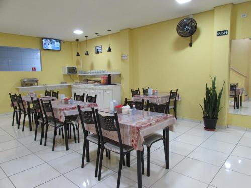 a dining room with tables and chairs and a kitchen at Hotel Biz a 8 minutos do Brás, a 15 minutos da 25 de março e a 8 minutos do Bom retiro in Sao Paulo