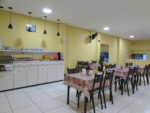 a restaurant with tables and chairs and a kitchen at Hotel Biz a 8 minutos do Brás, a 15 minutos da 25 de março e a 8 minutos do Bom retiro in São Paulo