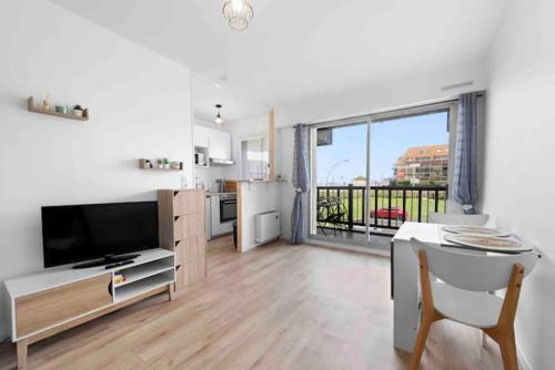 un salon avec une table et une grande fenêtre dans l'établissement Un Cocon au Bord de l'Océan Vue Partielle sur Mer, à Villers-sur-Mer
