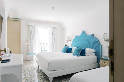 a bedroom with a bed and a blue headboard at Hotel Conca d'Oro in Positano