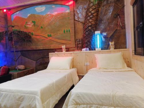2 Betten in einem Zimmer mit Wandgemälde in der Unterkunft Yaso Roof & Apartments in Amman