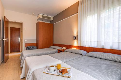una camera d'albergo con due letti e un vassoio di cibo di HOTEL GRAN VIA a Calera y Chozas