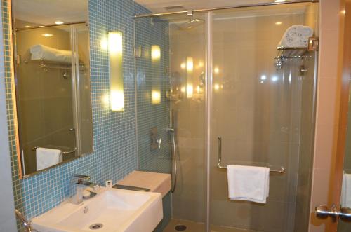 a bathroom with a glass shower and a sink at Peerless Hotel Hyderabad in Hyderabad