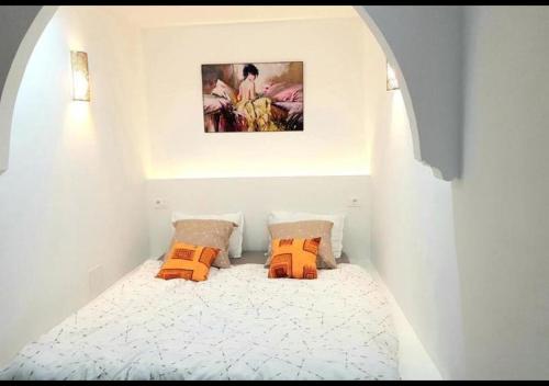 een kleine slaapkamer met een bed met oranje kussens bij The Arabesque House in La Marsa