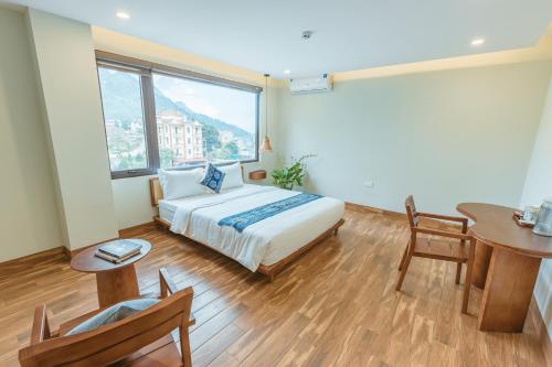 a hotel room with a bed and a table and a window at Sapa Yen Hotel in Sa Pa