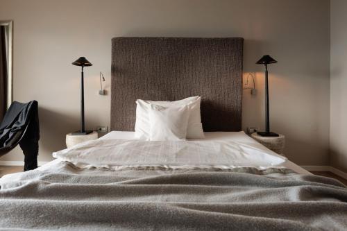 a bedroom with a large white bed with two lamps at Hotel KÜGLERHOF in Tirolo