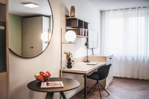um quarto com uma secretária, uma mesa e um espelho em The Circus Living em Berlim