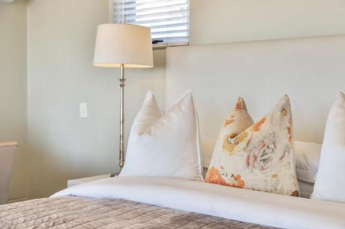 a bedroom with a bed with white pillows and a lamp at O on Kloof Boutique Hotel & Spa in Cape Town