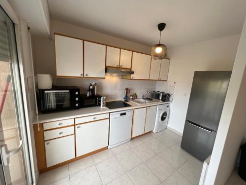 une cuisine avec des armoires blanches, un évier et un micro-ondes dans l'établissement Appartemment Cozy Vue sur Mer, à Marseille