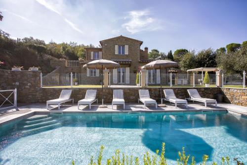 a swimming pool with chairs and umbrellas in front of a house at Villa Chiara in Cortona