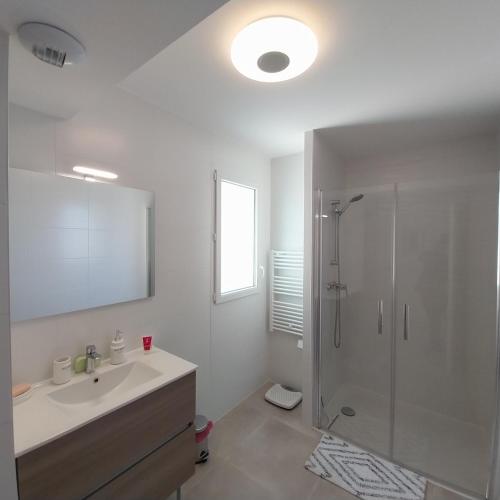 une salle de bain blanche avec une douche et un lavabo dans l'établissement Superbe T3 wifi climatisé, Le Sunset Lodge, Narbonne Plage, à Narbonne-Plage