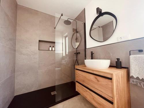 uma casa de banho com um lavatório e um espelho em Bungalow + Piscina independiente em La Oliva