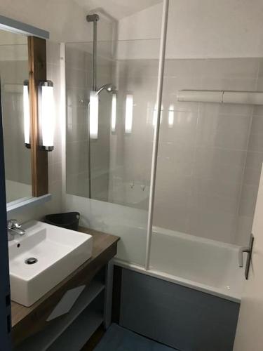 une salle de bain blanche avec un lavabo et une douche dans l'établissement Appartement vue piscine et golf, à Talmont-Saint-Hilaire