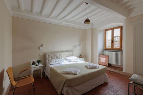 una camera bianca con un letto e una sedia di Appartamento Mancini a Cortona