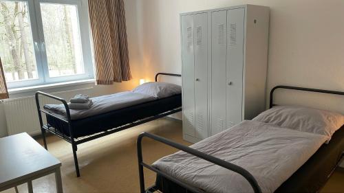 a room with two beds and a cabinet and a window at A2rooms in Lehnin