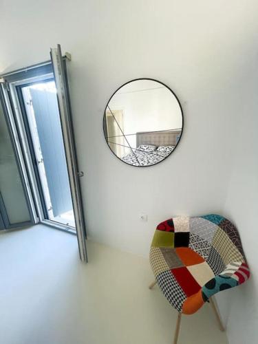 a mirror and a chair next to a window at Aggelos Apartment Central in Antiparos in Andiparos