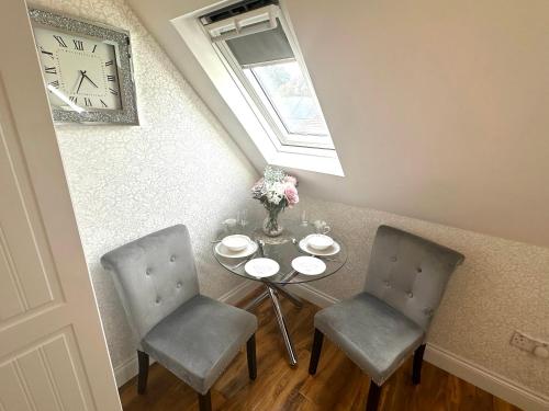 a table with two chairs and a clock on the wall at ElMurrs in Bournemouth