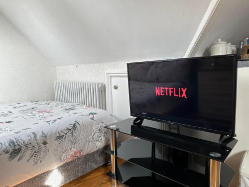 a television on a table in a bedroom with a bed at ElMurrs in Bournemouth
